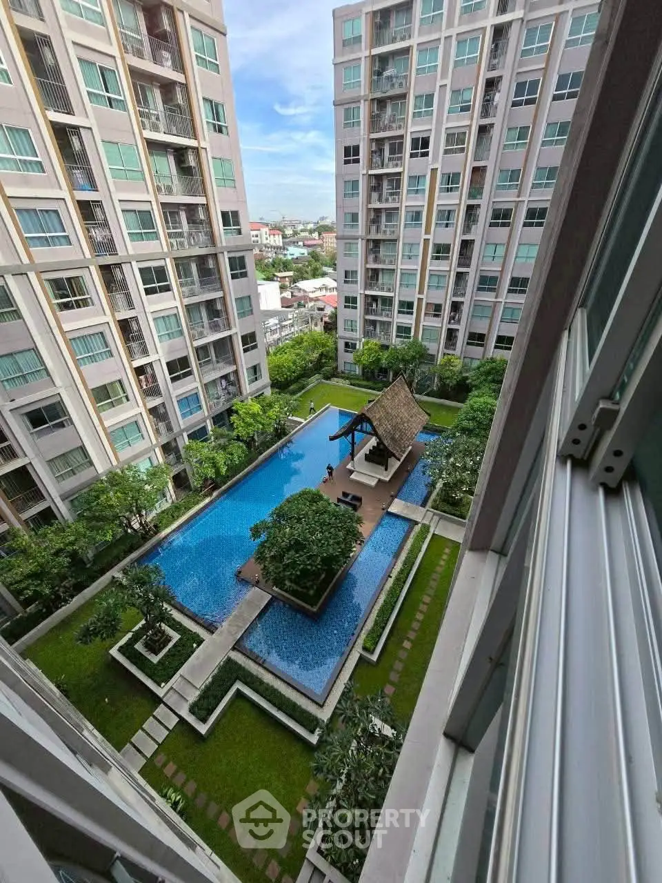 Stunning view of modern apartment complex with central pool and lush greenery.