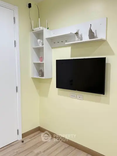 Modern living room corner with mounted TV and decorative shelves