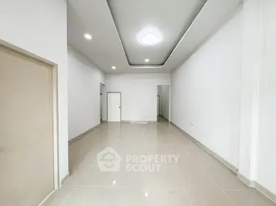 Spacious modern living room with elegant ceiling design and tiled flooring.