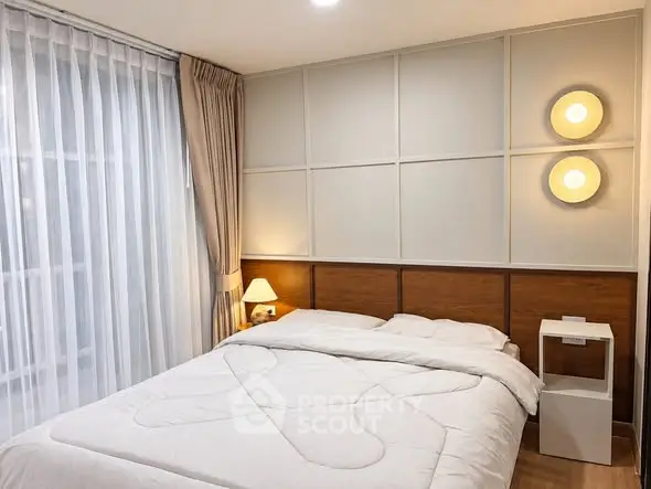 Cozy modern bedroom with elegant lighting and large window for natural light.