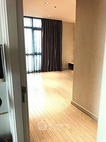 Spacious room with wooden flooring and large window with curtains