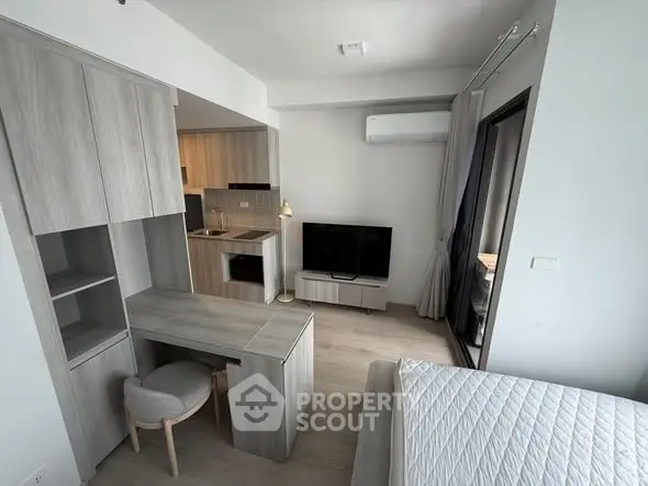 Modern studio apartment with open kitchen and cozy living area, featuring sleek furniture and natural light.