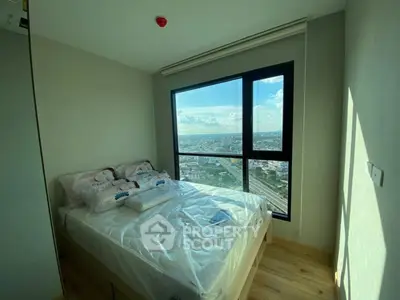 Bright bedroom with large window offering stunning city view, featuring a cozy bed and wooden flooring.