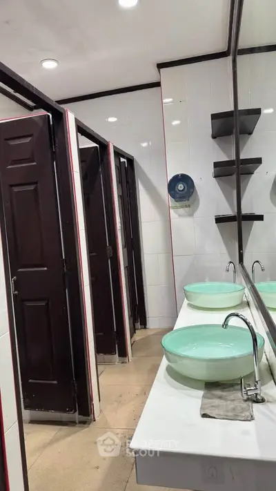 Modern bathroom with dual sinks and partitioned stalls in a sleek design.