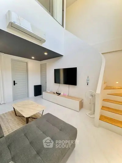 Modern living room with sleek design, featuring a wall-mounted TV, stylish staircase, and air conditioning unit.
