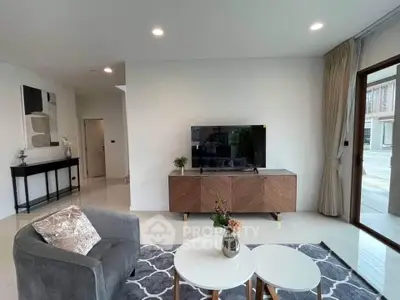 Modern living room with stylish decor and natural light, featuring a sleek TV stand and cozy seating area.