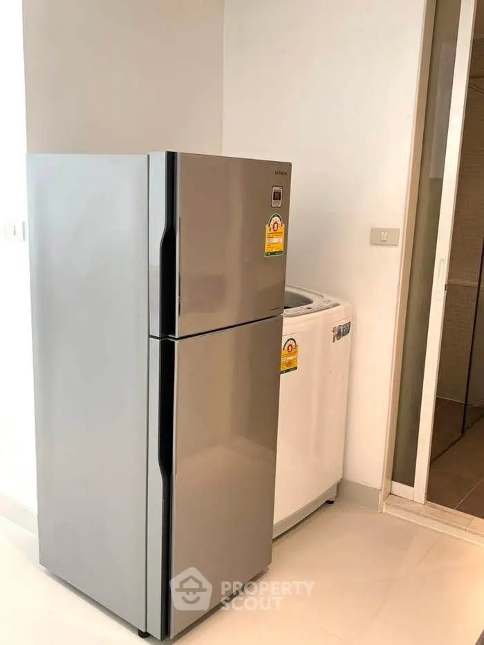 Modern kitchen with sleek fridge and washing machine in bright space.