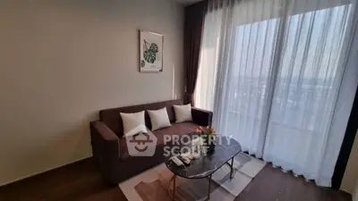 Stylish living room with cozy sofa and elegant coffee table near large window with sheer curtains.