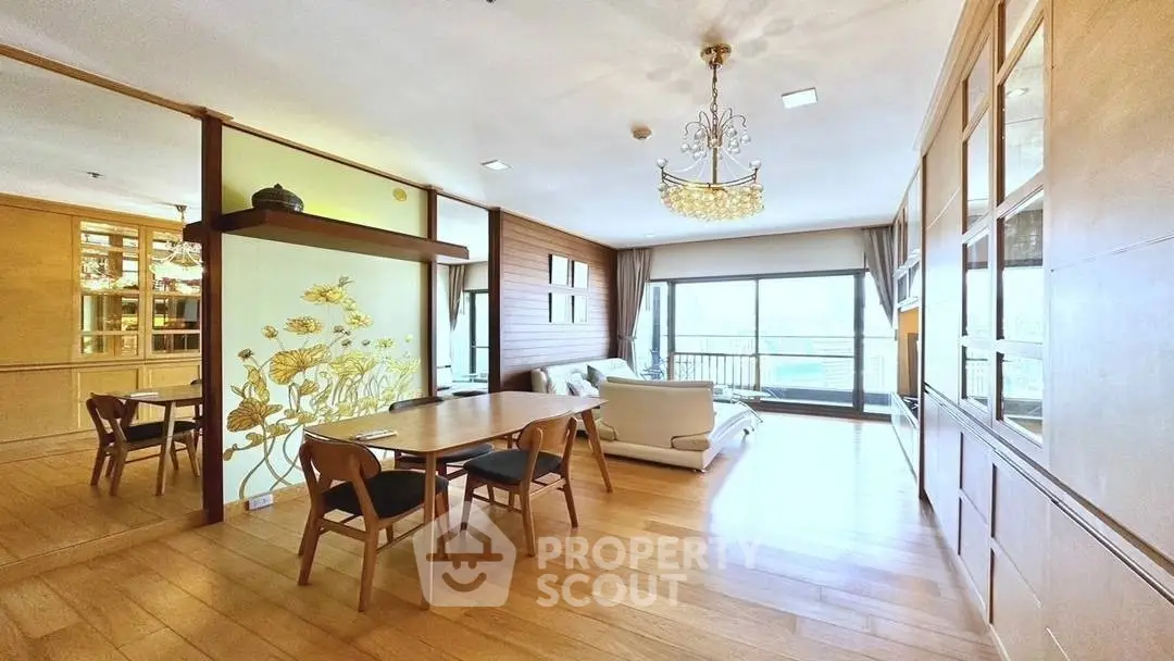 Spacious living room with elegant chandelier and large windows offering natural light.