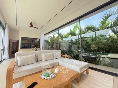 Luxurious living room with pool view and modern decor in tropical setting.