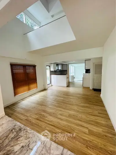 Spacious open-plan living area with wooden flooring and abundant natural light.
