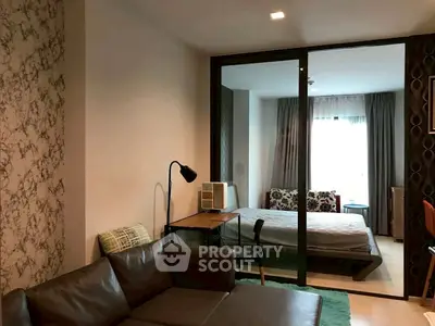 Modern condo interior with cozy living room and stylish bedroom separated by glass partition.