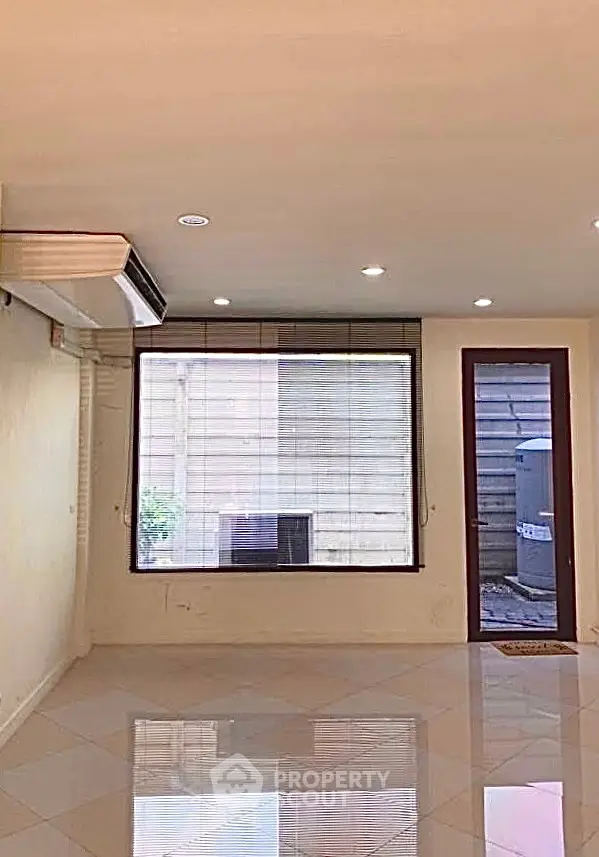 Spacious living room with large window and modern air conditioning unit.