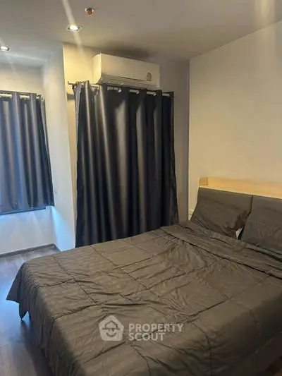 Cozy bedroom with dark curtains and modern air conditioning unit.