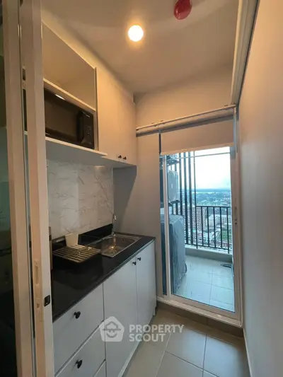 Compact kitchen with balcony view, featuring sleek cabinetry and modern appliances.