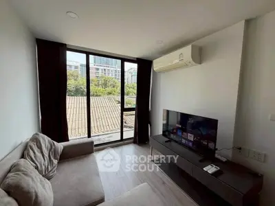 Modern living room with large window and city view, featuring cozy sofa and sleek entertainment unit.