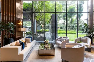 Luxurious living room with large windows overlooking a lush garden, featuring elegant furniture and decor.