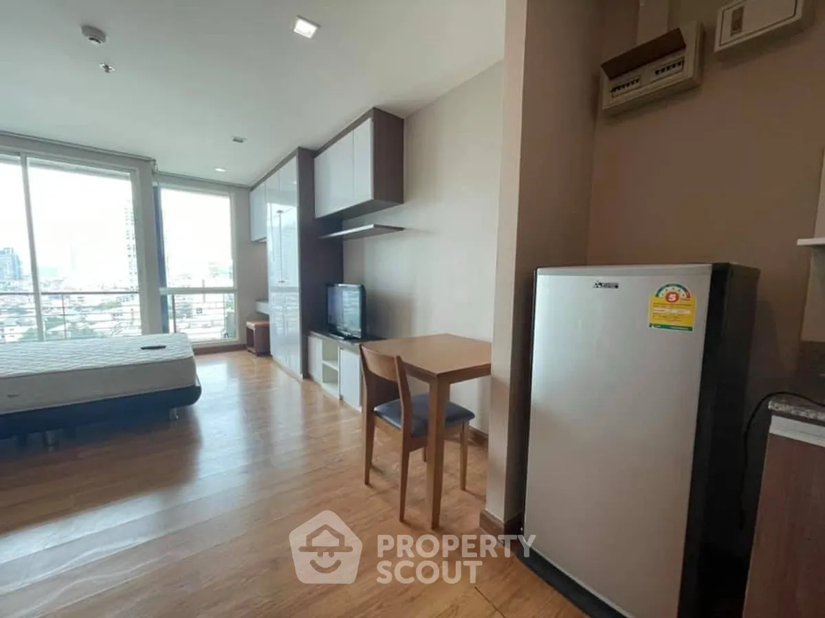 Modern studio apartment with city view, featuring a cozy living area and compact kitchen.