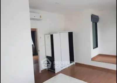 Spacious bedroom with wooden flooring and modern wardrobe in a bright apartment.