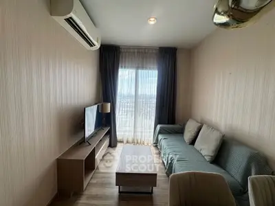 Modern living room with cozy sofa, TV, and large window offering natural light.