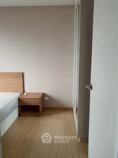 Cozy bedroom with wooden flooring and minimalist furniture design.