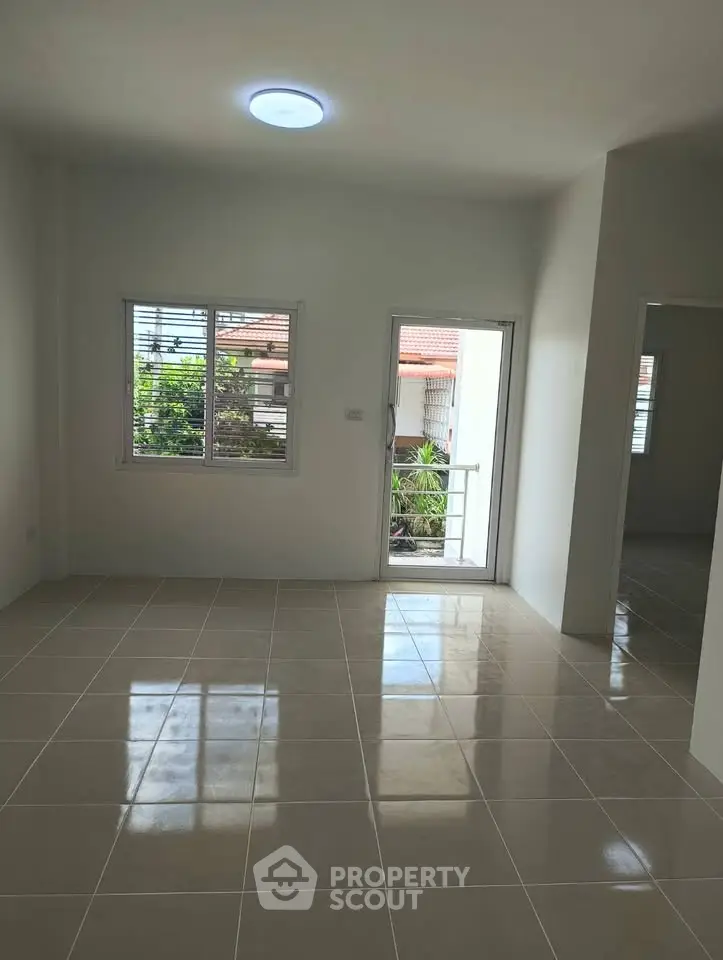 Spacious tiled living room with natural light and balcony access in modern home.