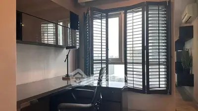 Modern study room with sleek desk, chair, and large window with shutters in urban apartment.