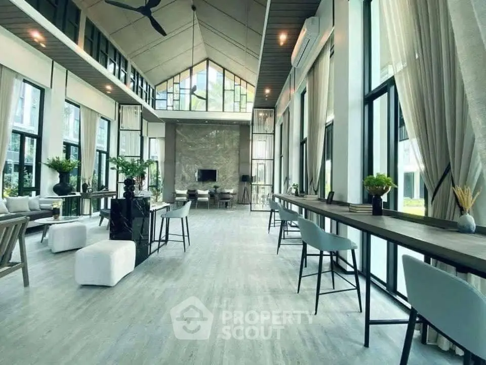 Spacious modern living room with high ceilings and large windows, featuring elegant decor and ample natural light.