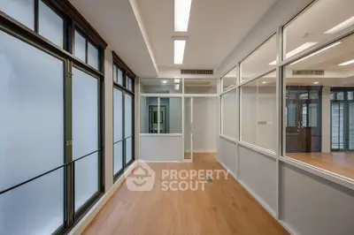 Spacious modern office space with large windows and wooden flooring.