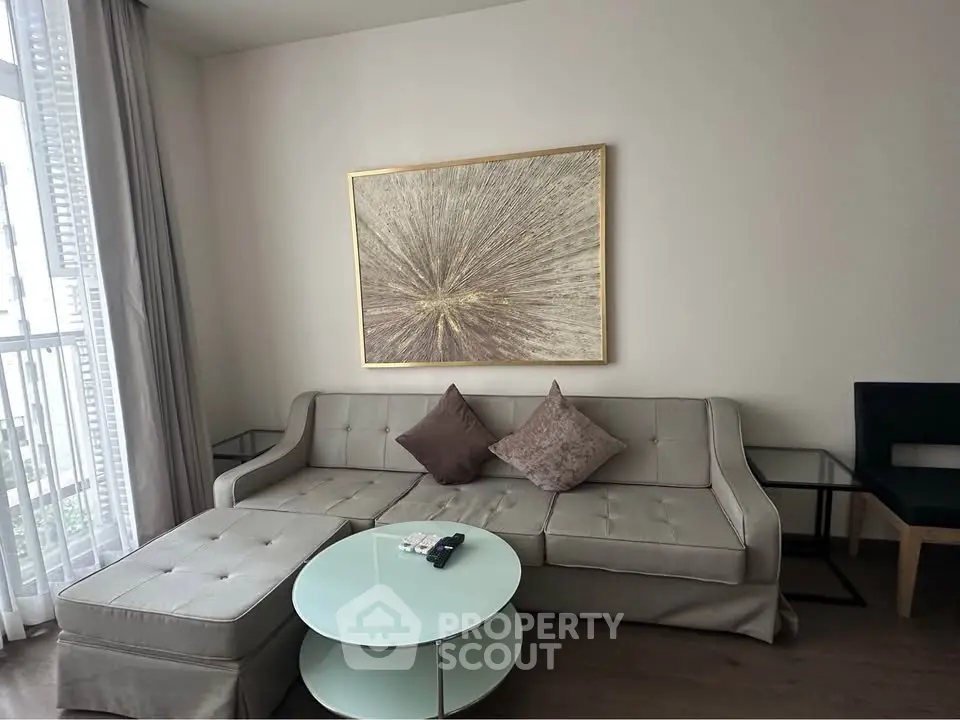 Modern living room with stylish sofa, abstract art, and natural light from large window.