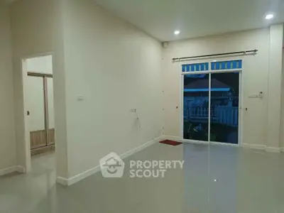 Spacious empty living room with sliding glass door leading to a cozy backyard