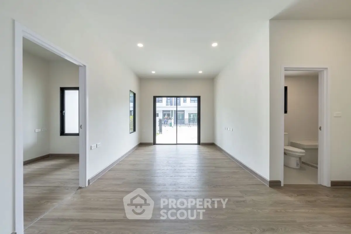 Spacious modern interior with wooden flooring and large windows, ideal for customization.