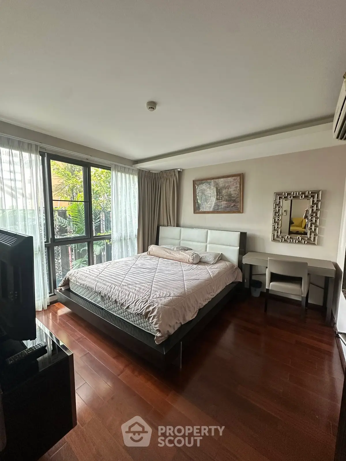 Spacious bedroom with elegant decor and large windows for natural light.