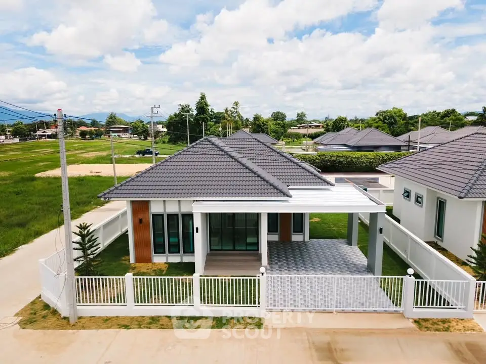 Modern single-story house with spacious yard and tiled roof in suburban neighborhood.