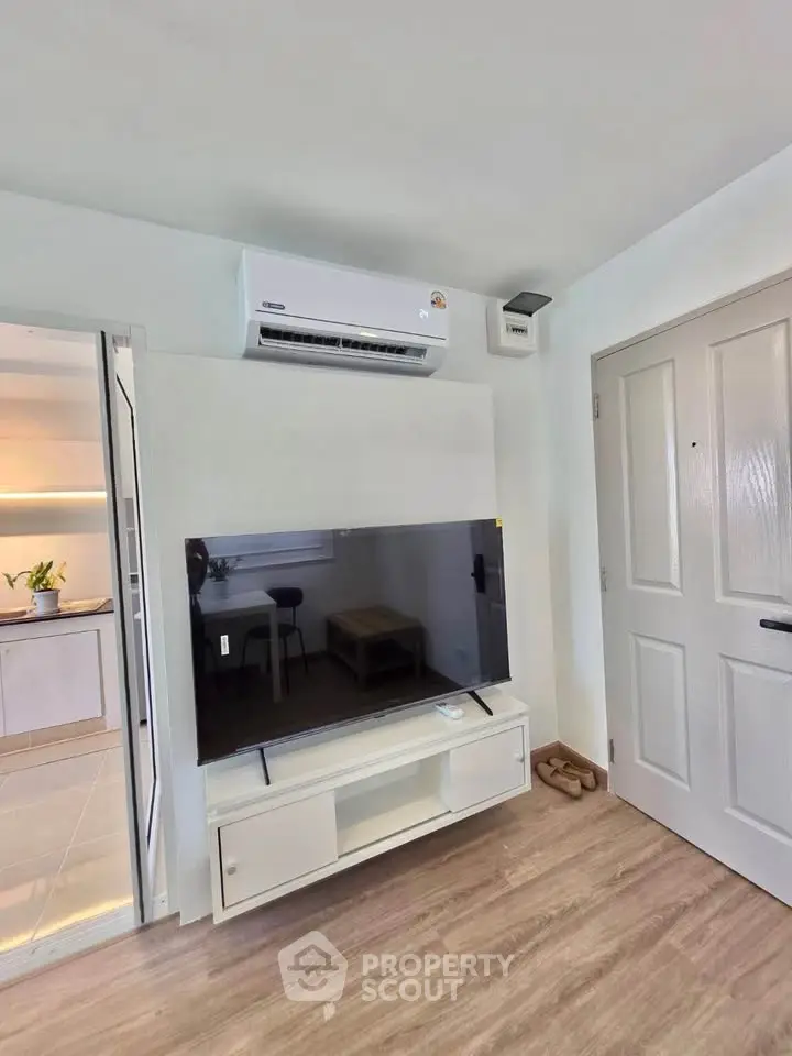 Modern living room with sleek TV setup and air conditioning, featuring stylish wooden flooring.