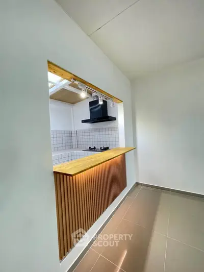 Modern kitchen with open layout and gas stove, featuring sleek wooden accents and tiled backsplash.