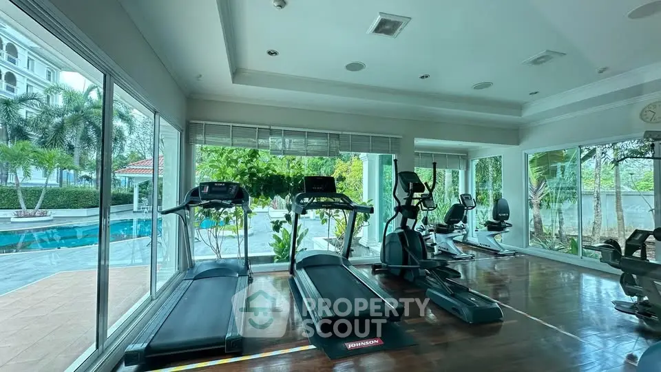 Luxurious gym with pool view, featuring modern exercise equipment and large windows for natural light.