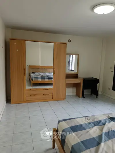 Spacious bedroom with wardrobe and desk, tiled floor, and cozy bed.