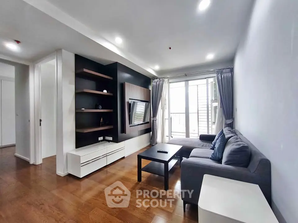 Modern living room with sleek design, wooden flooring, and large window for natural light.