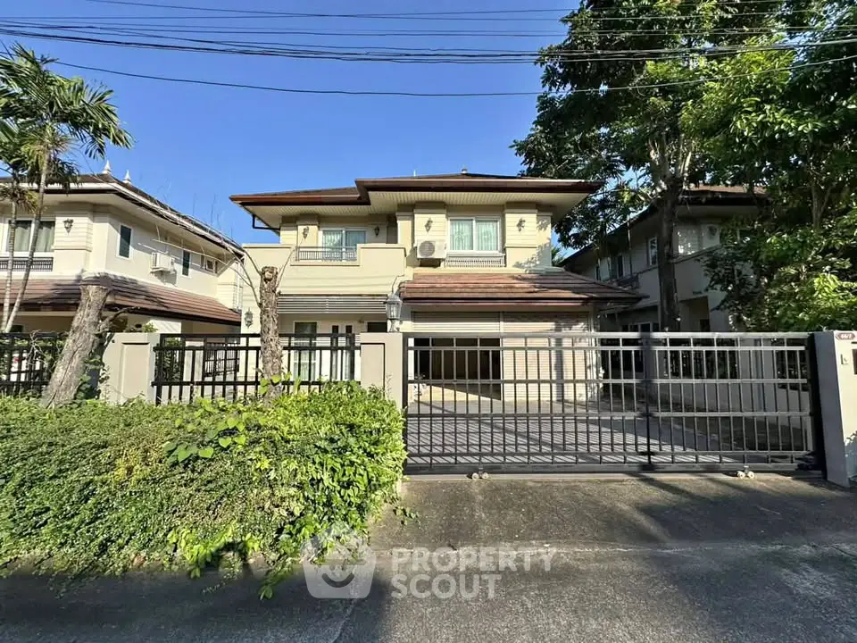 Charming two-story house with gated entrance and lush greenery in a serene neighborhood.