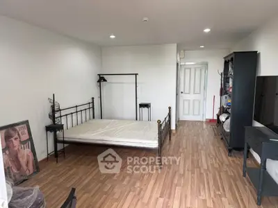 Spacious bedroom with wooden flooring and minimalist decor, featuring a metal bed frame and ample storage space.