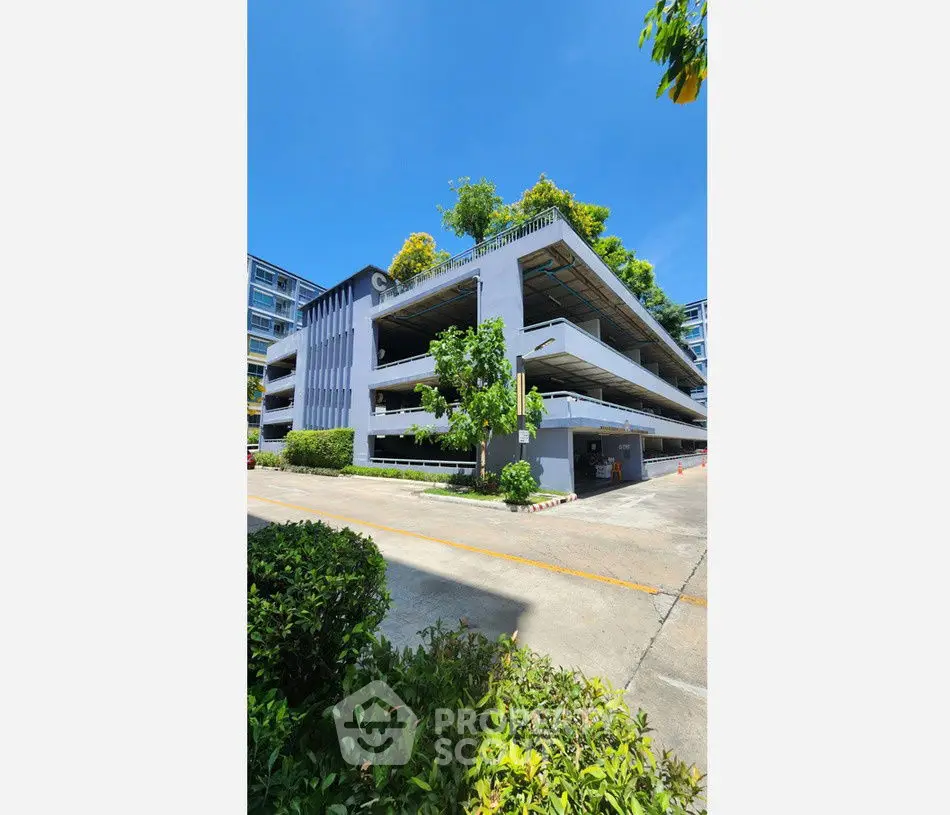 Modern multi-level parking structure with lush greenery and clear blue sky.