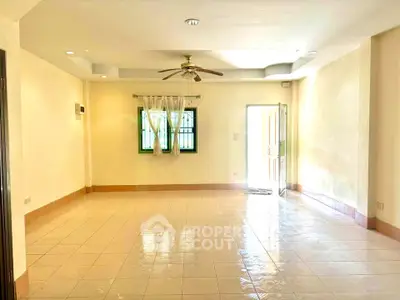 Spacious empty living room with ceiling fan and tiled floor, ready for customization.