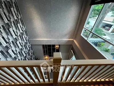 Stunning loft view with modern design and large windows overlooking greenery.