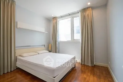 Spacious bedroom with wooden flooring and large window for natural light.