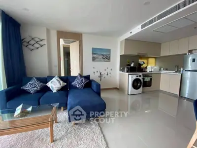 Modern living room with blue sofa, open kitchen, and washing machine in stylish apartment.