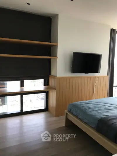 Modern bedroom with wooden accents and wall-mounted TV, featuring large window and cozy bed.