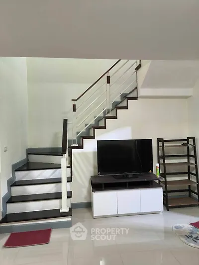 Modern living room with sleek staircase and TV unit, perfect for stylish urban living.