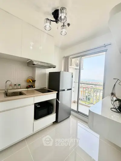 Modern kitchen with sleek appliances and balcony view in a bright apartment.