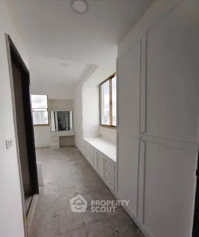 Spacious hallway with built-in storage and large windows in modern apartment.